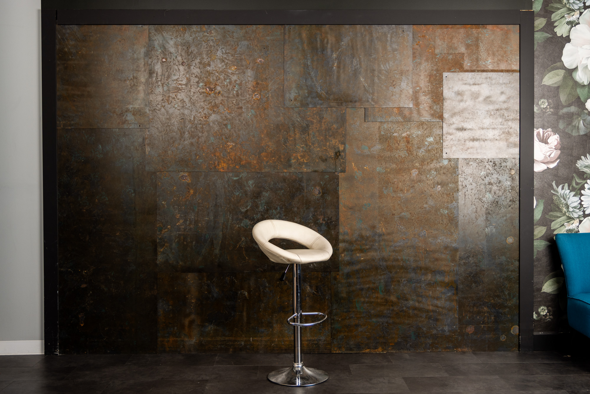 Oxidized metal patina wall with a cream stool