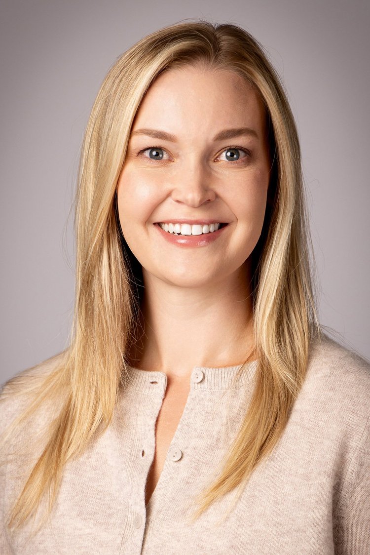 Woman with blonde hair in a cream cardigan on a soft grey backdrop