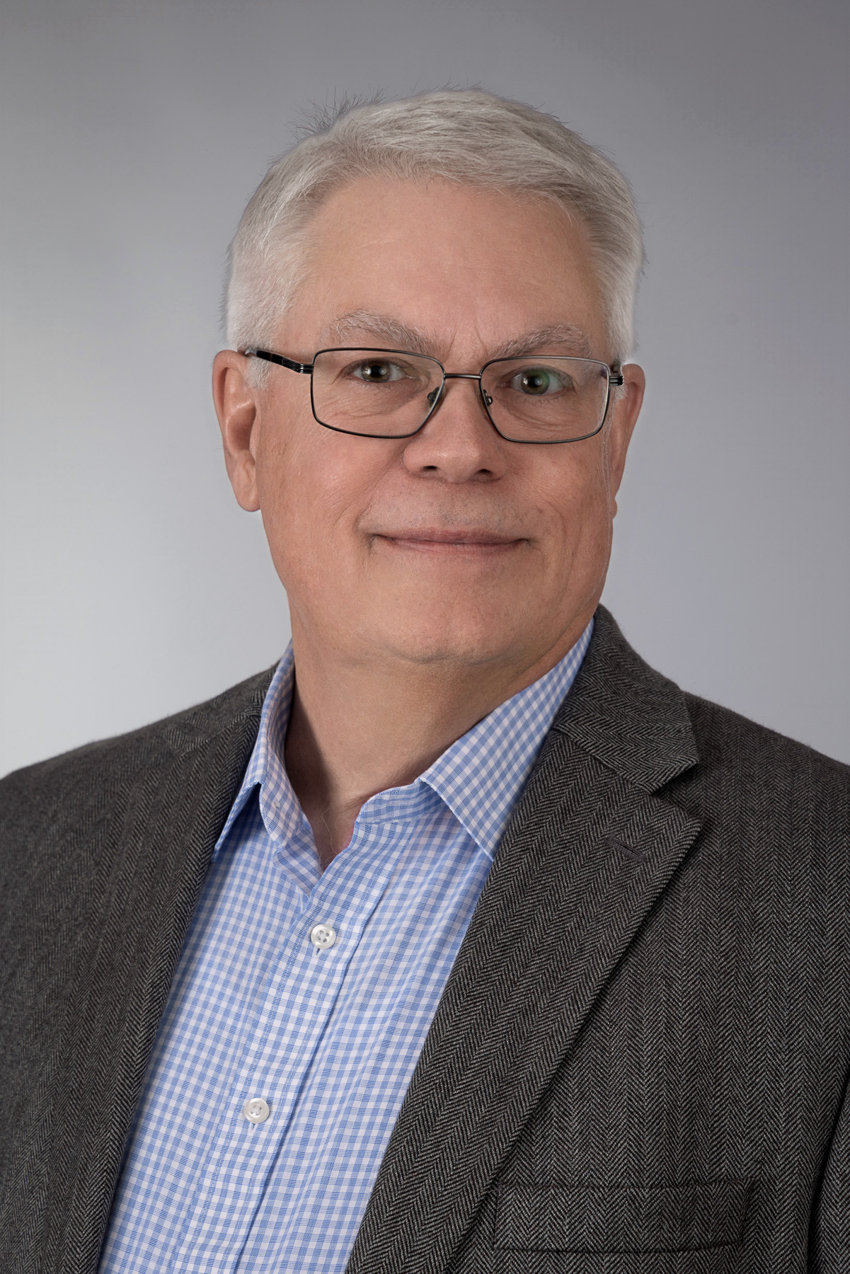 Executive with white hair, glasses and a herringbone jacket