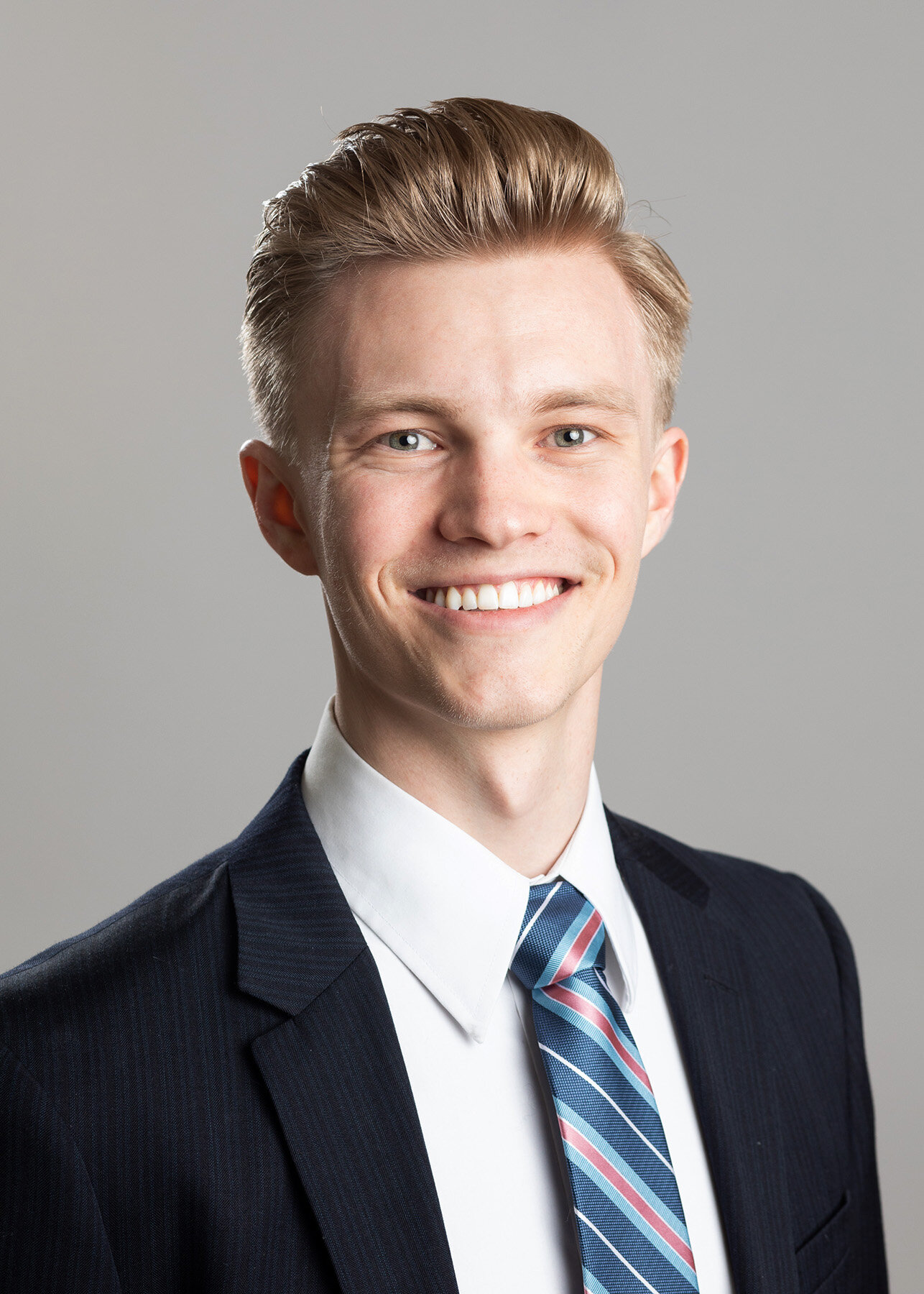 Young professional man with blonde hair in a navy suit and striped tie