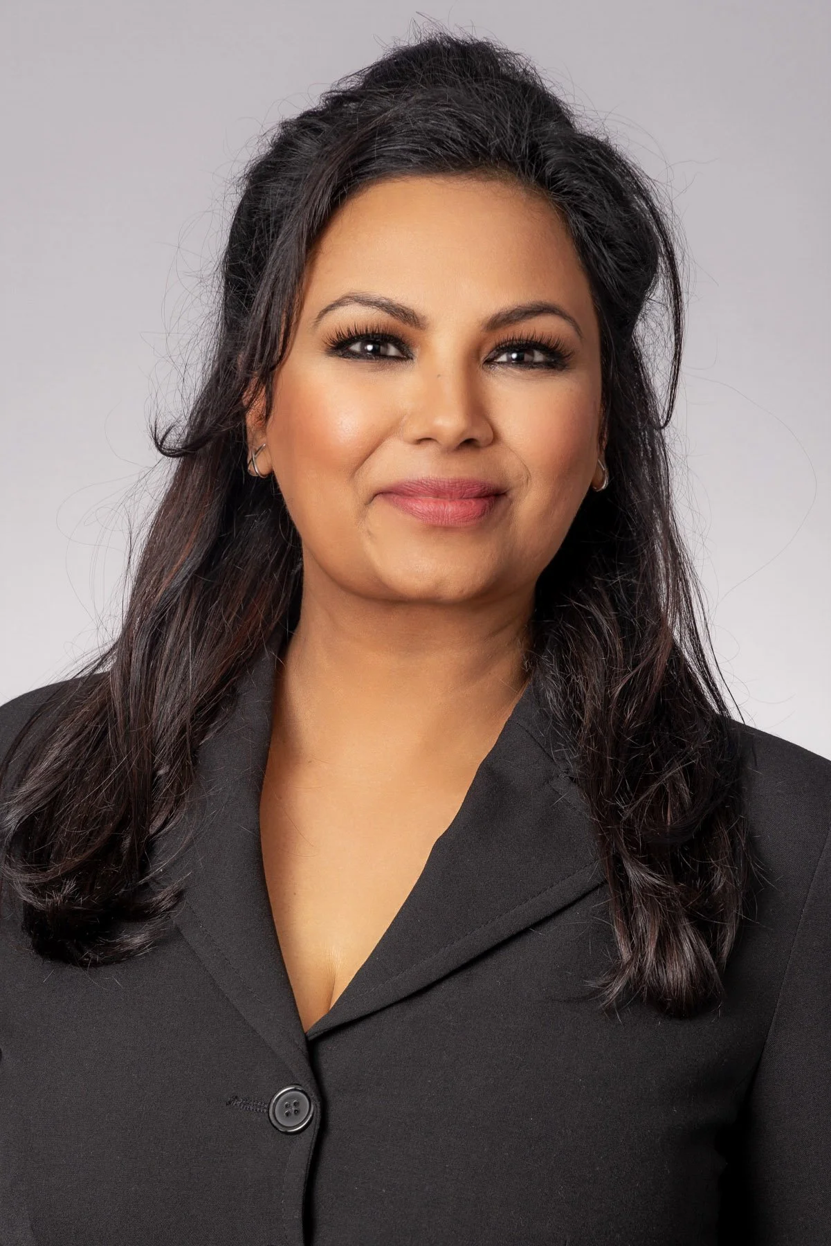 Professional woman in a charcoal blazer on a soft grey backdrop