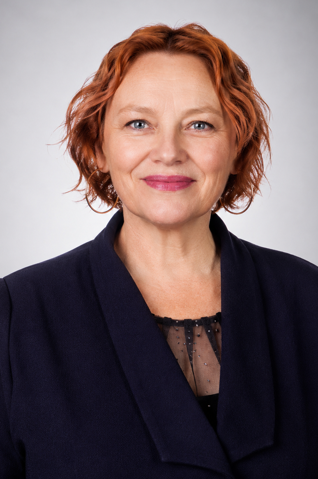 Professional woman with auburn hair in a navy jacket