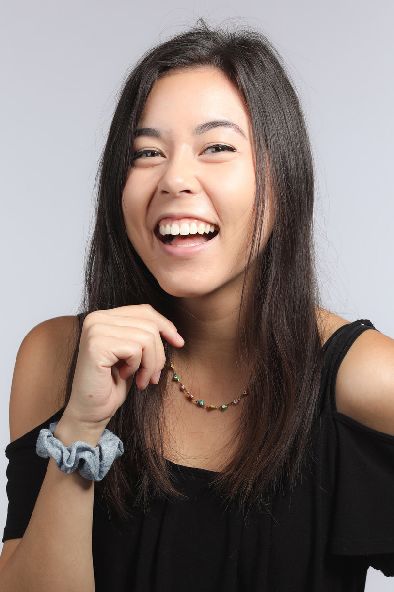 Laughing young woman in a black top on a light grey backdrop