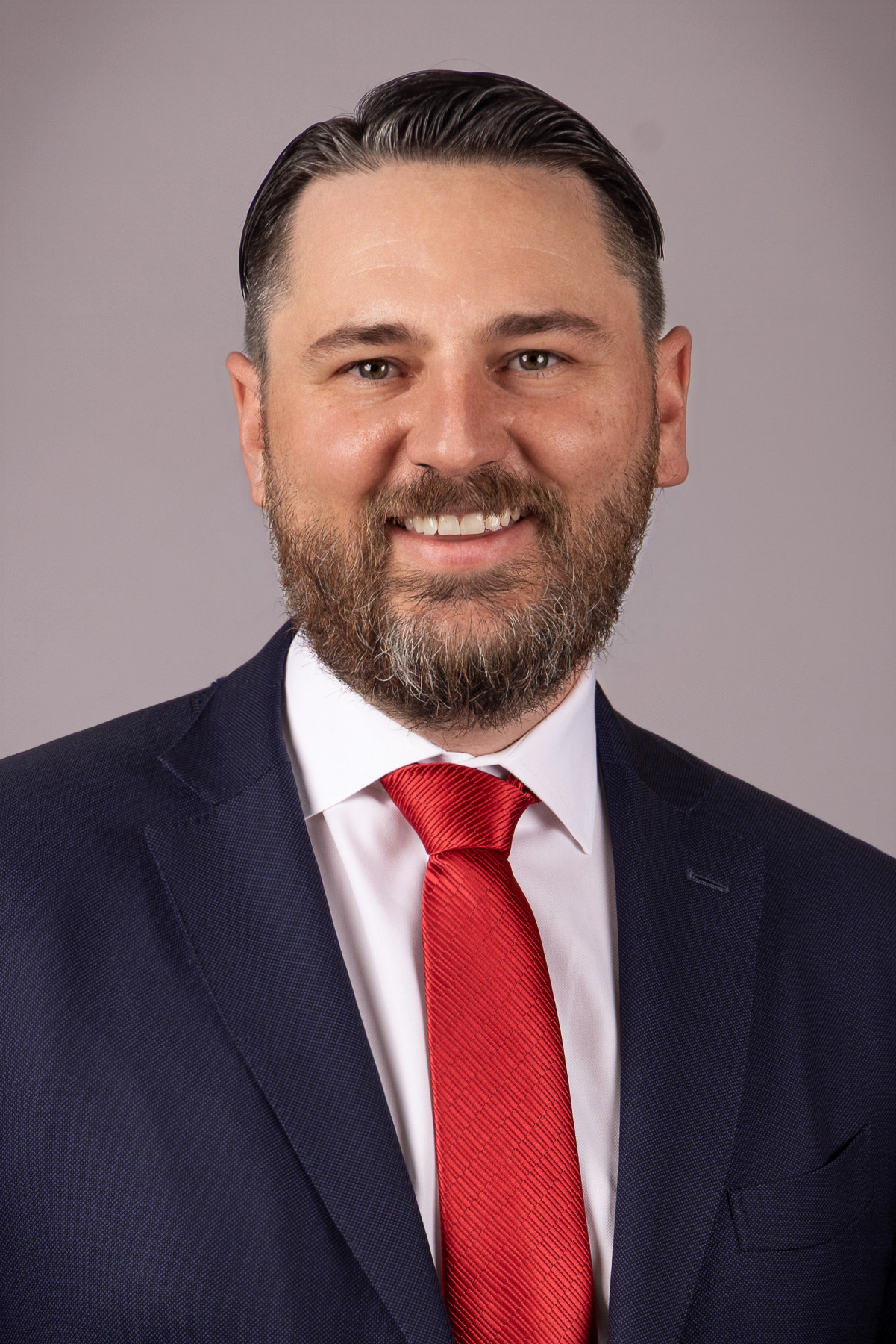 Bearded executive in a navy suit with a red tie