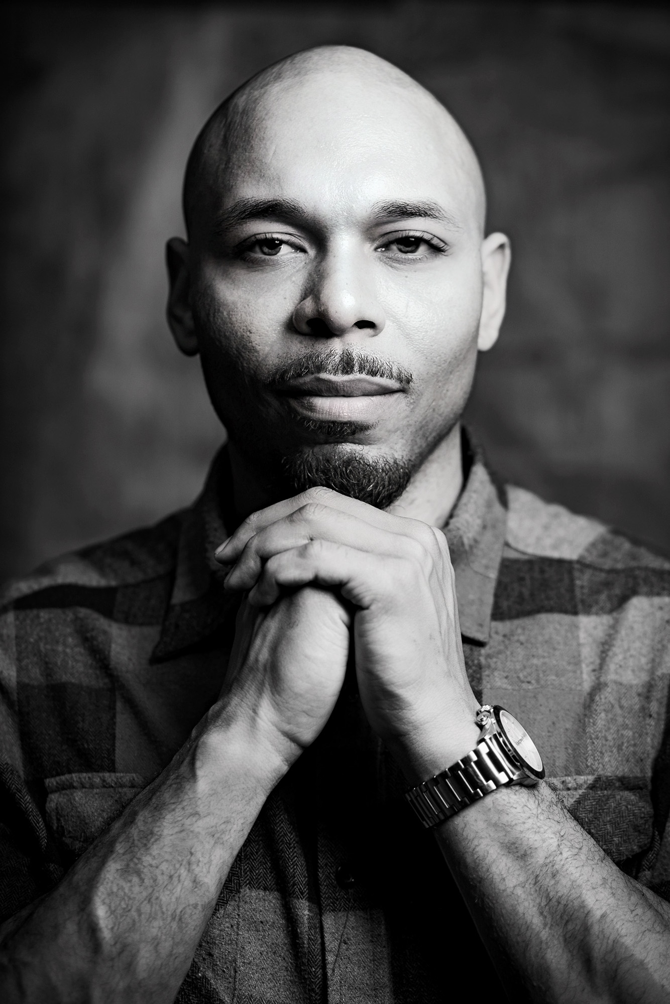 Black and white portrait of a man with hands clasped under his chin