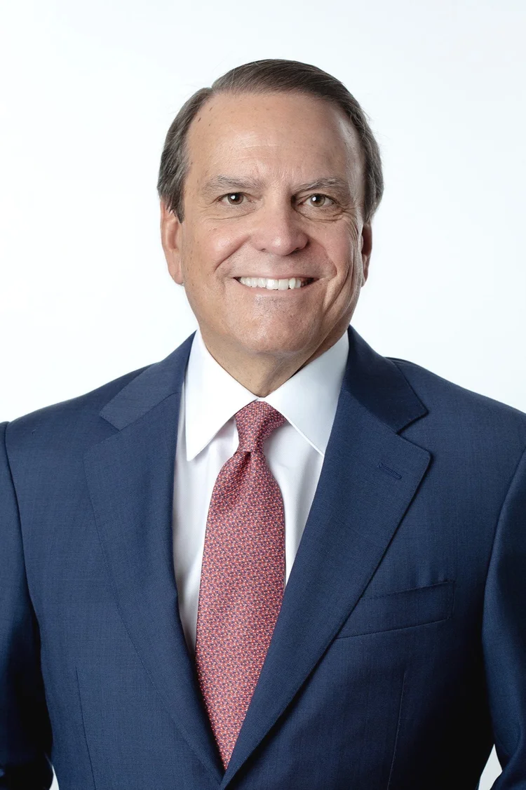 Senior executive in a navy suit and red patterned tie on white