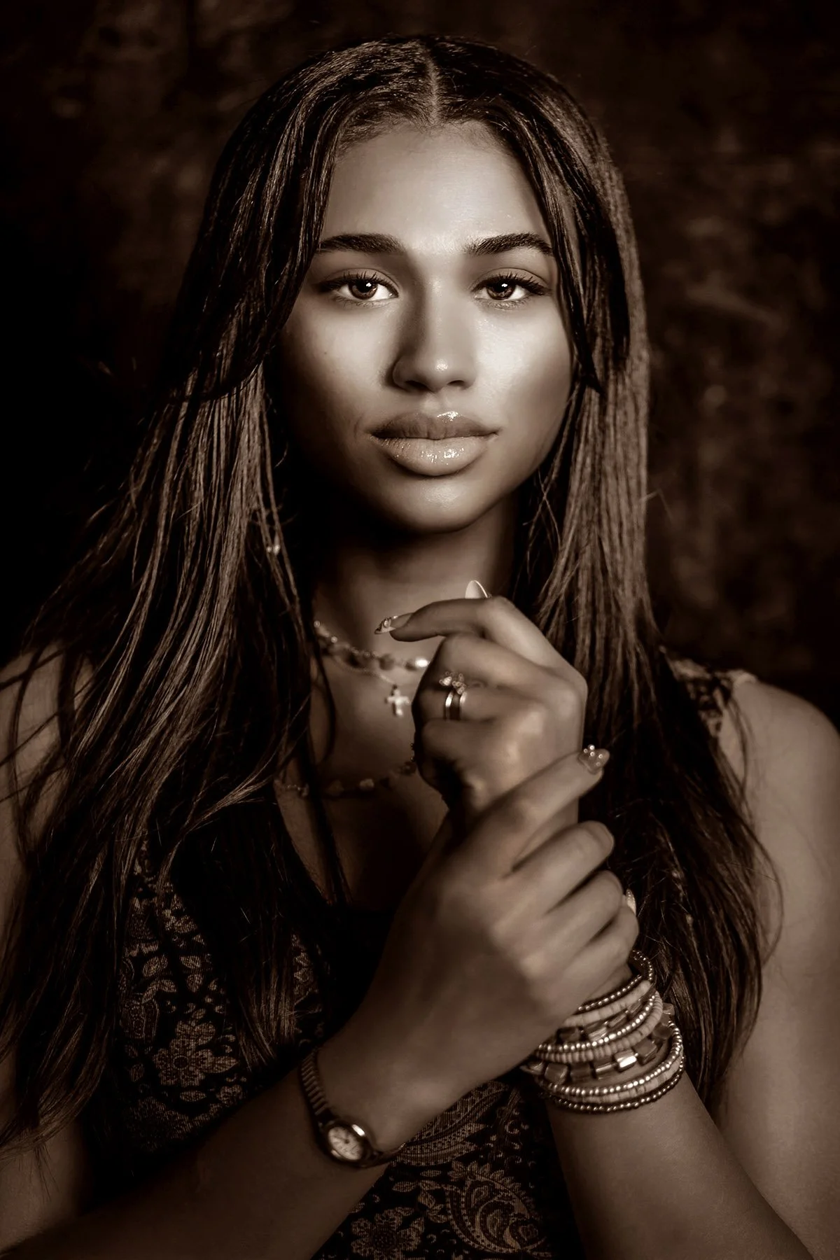 Sepia-toned portrait of a young woman with long hair and layered jewelry